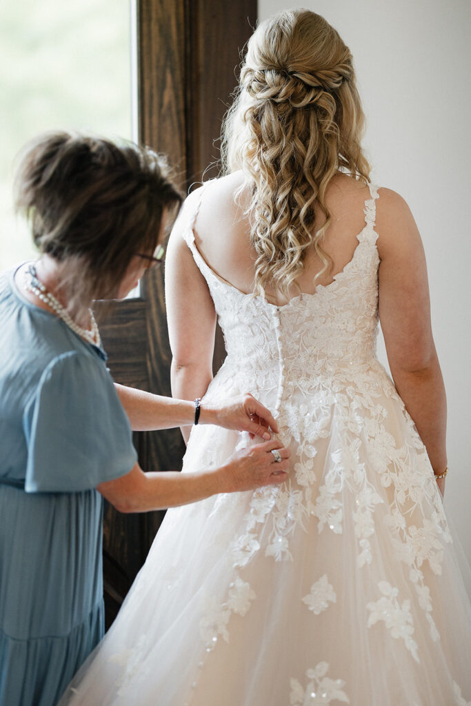 mother of the bride helping her with her wedding dress