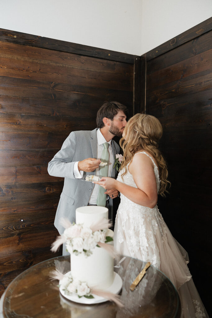 bride and groom kissing after trying their wedding cake 