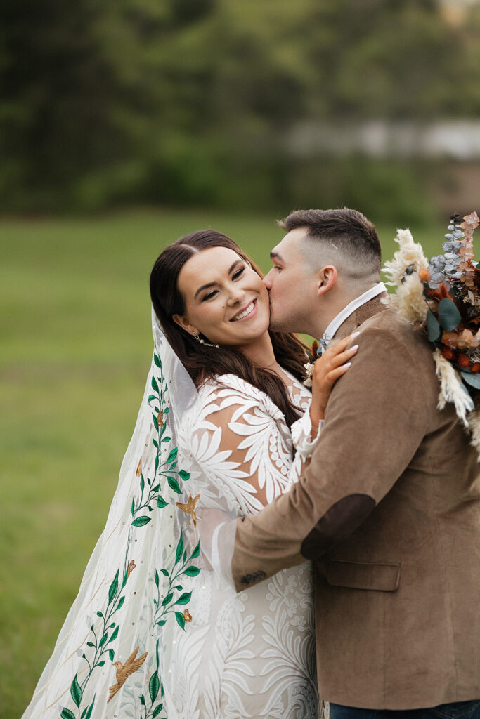 groom kissing the bride on the cheek 