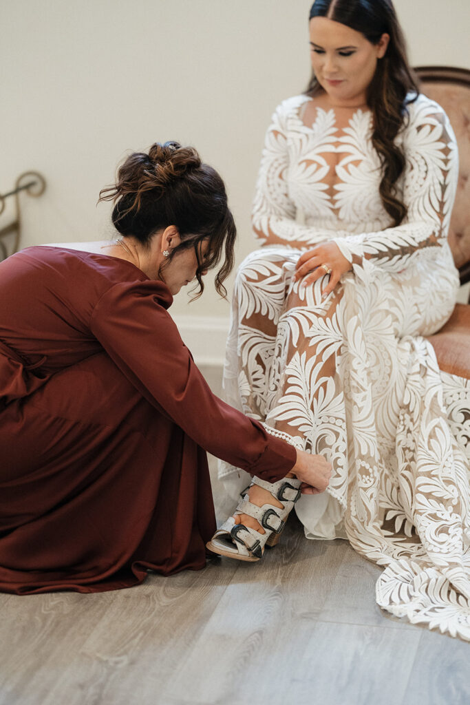 mother of the bride helping her with her wedding shoes 