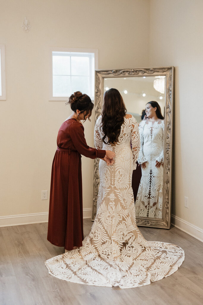 mother of the bride helping her with her wedding dress