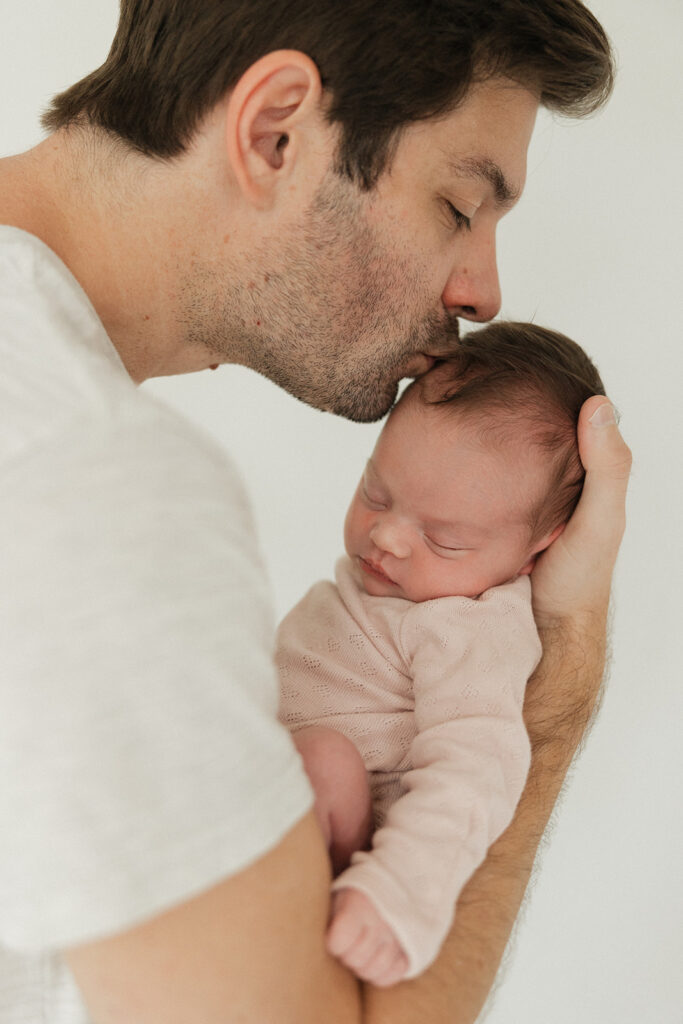 dad kissing his newborn on the head 