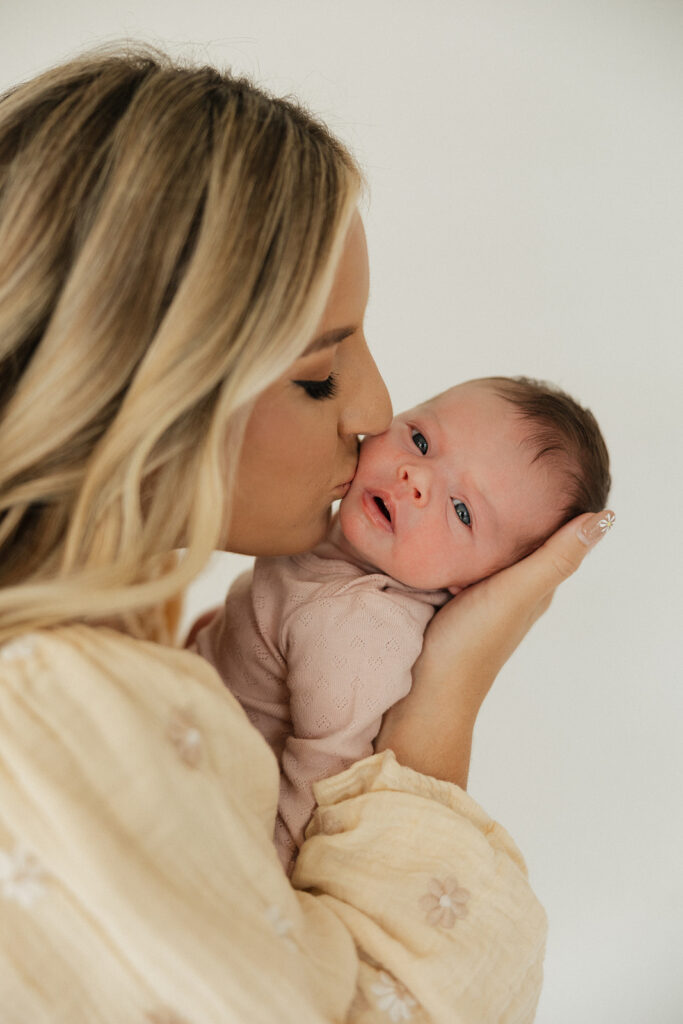 mom kissing her newborn on the cheek