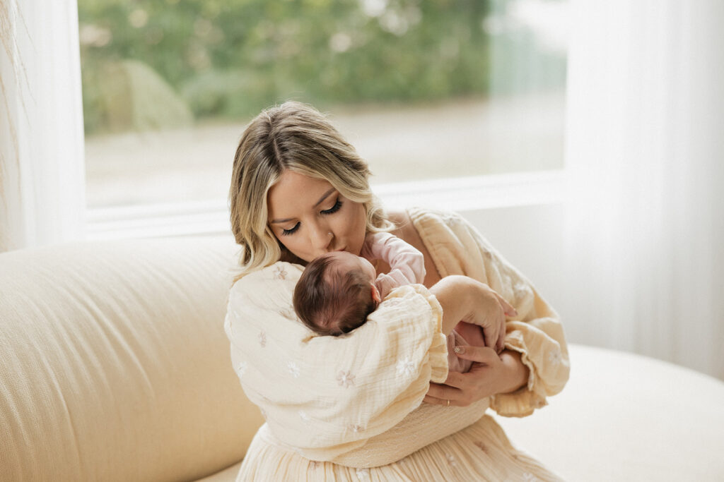 mom kissing her newborn on the forehead 