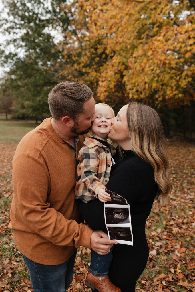 mom and dad kissing their little boy - fall pregnancy announcement