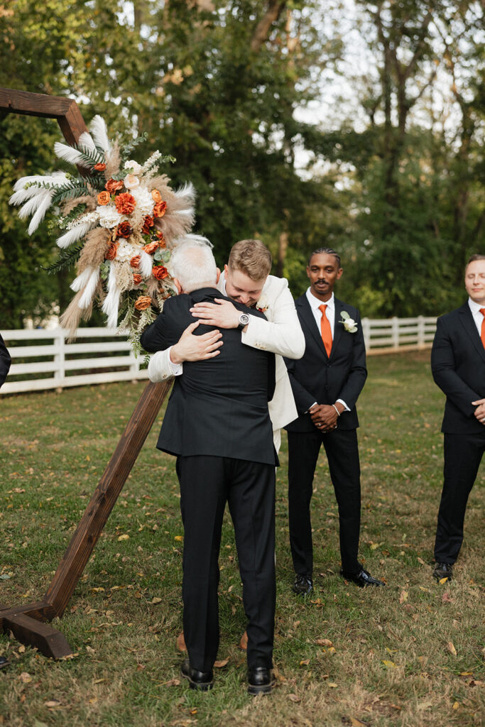 groom hugging the father of the bride at the altar 