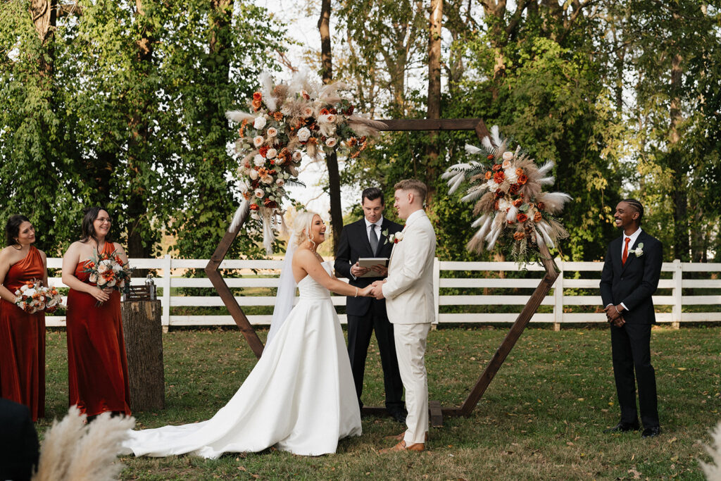 stunning portrait of the bride and groom holding hands at their colorful boho wedding ceremony 