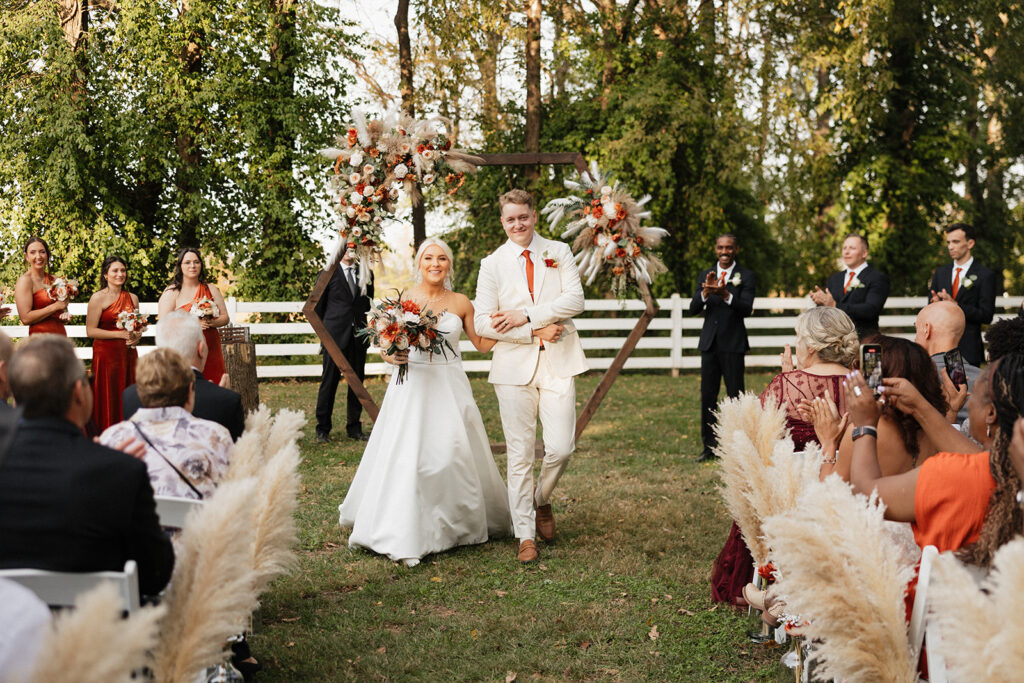 bride and groom heading to their colorful boho wedding reception