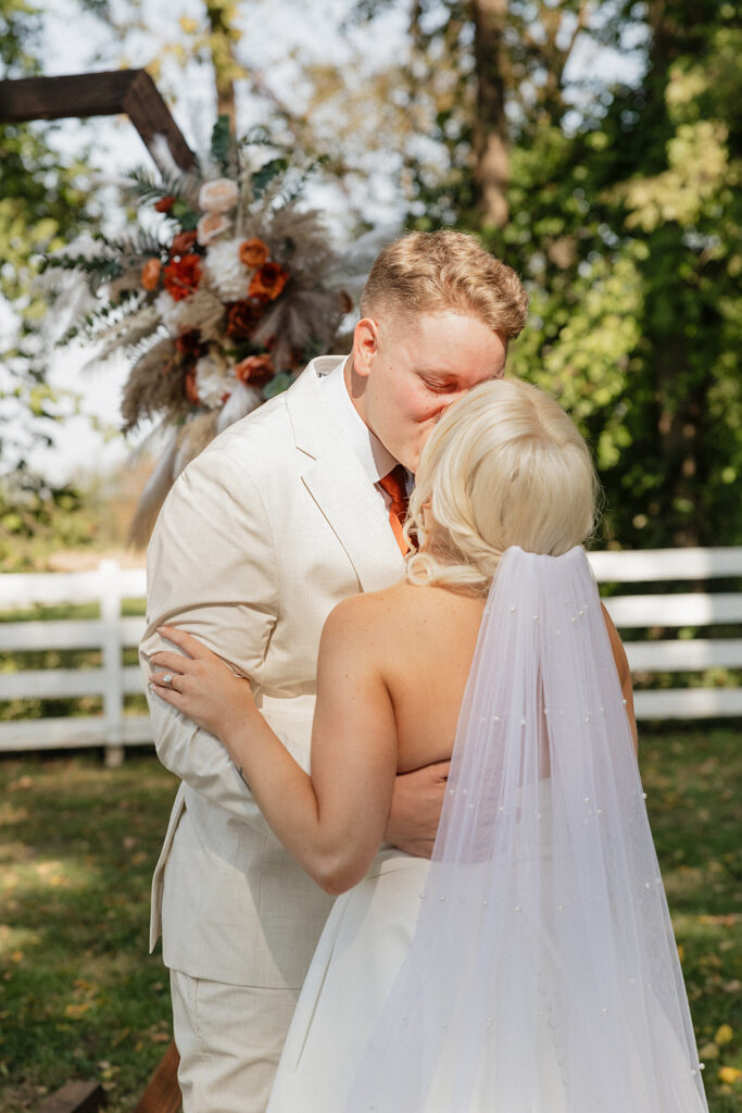 portrait of the bride and groom kissing after their first look