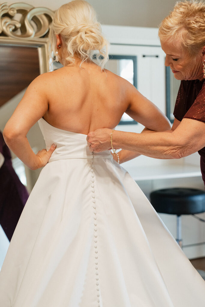 mother of the bride helping her with the wedding dress