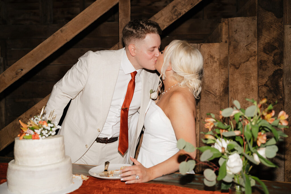 newlyweds kissing after cutting their wedding cake 