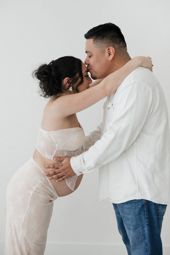 couple kissing during their studio maternity photoshoot