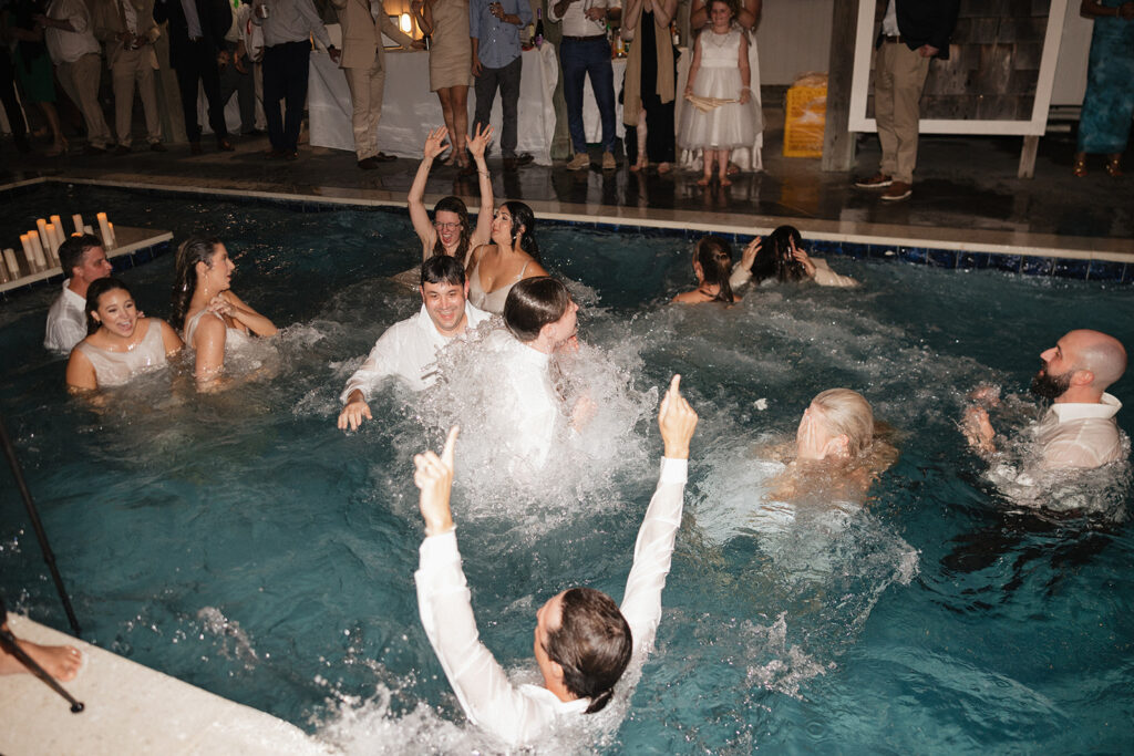 wedding guests jumping in the pool at the reception party