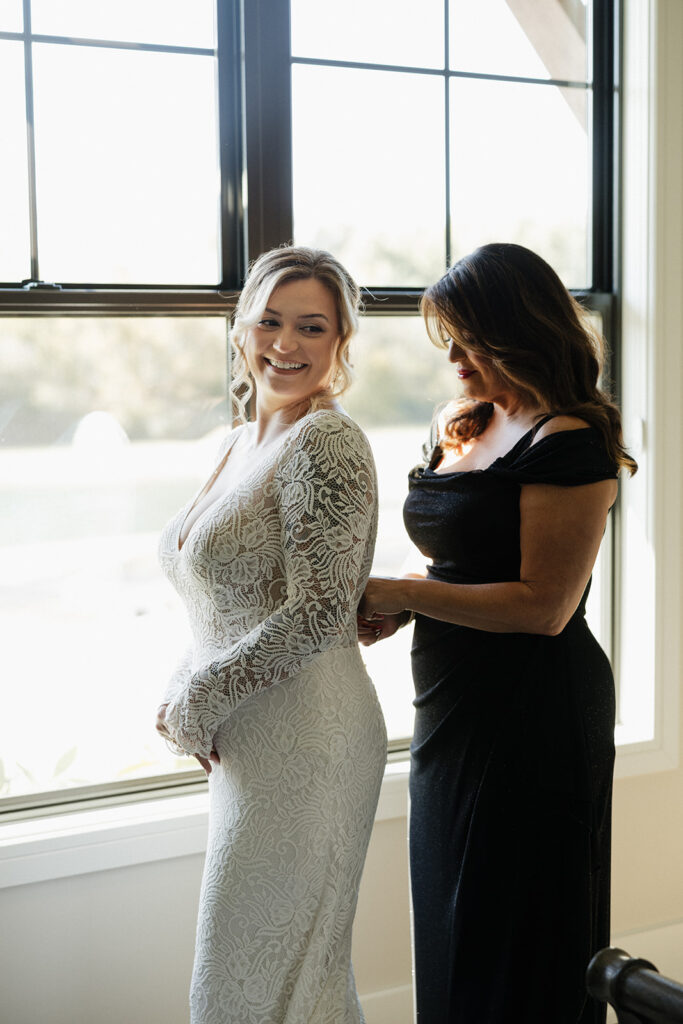 mother of the bride helping her with her wedding dress
