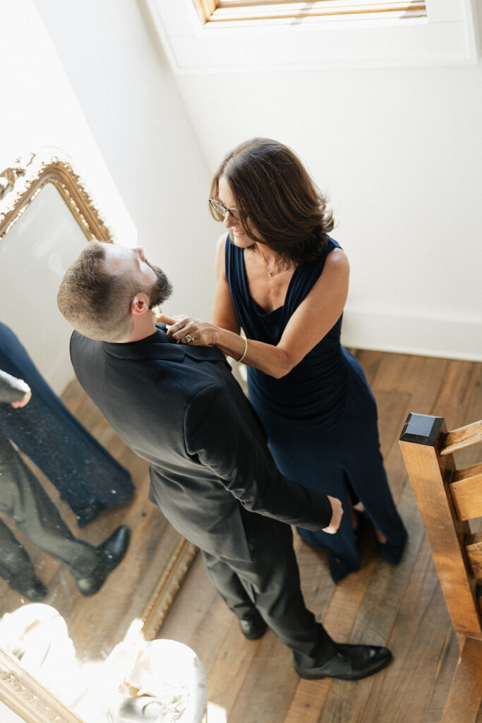 mother of the groom helping him before heading to the ceremony