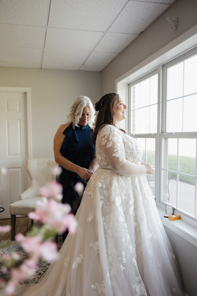 mother of the bride helping her with her wedding dress