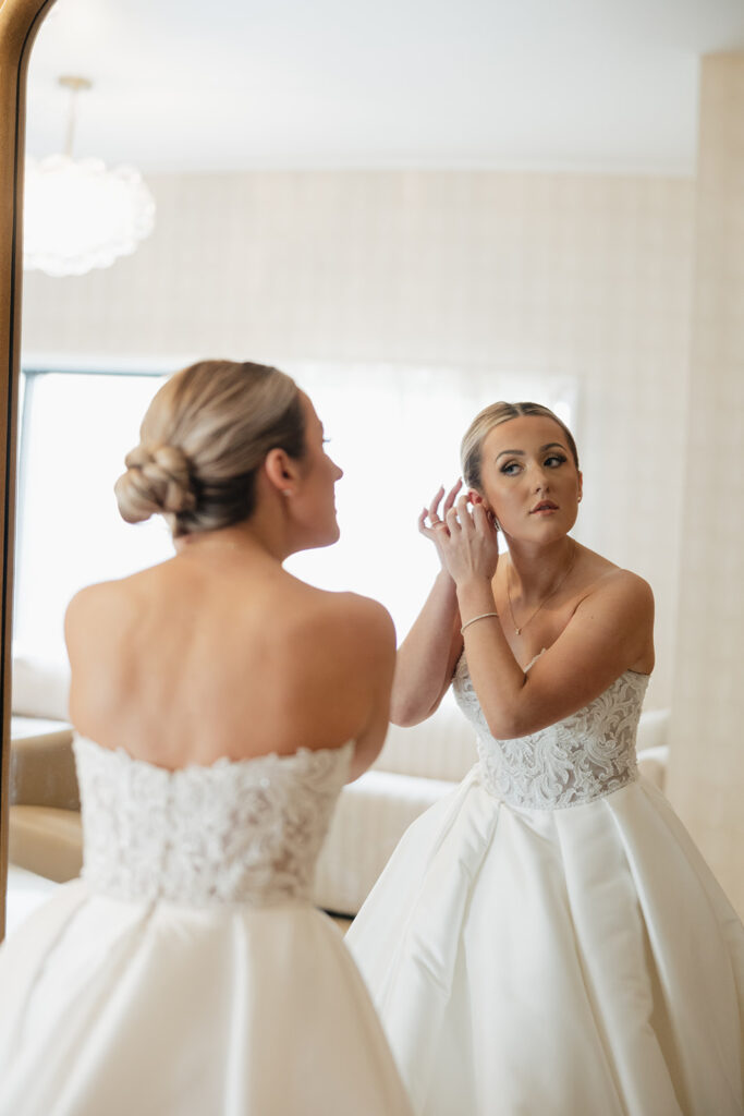 bride putting on her jewelry before the ceremony