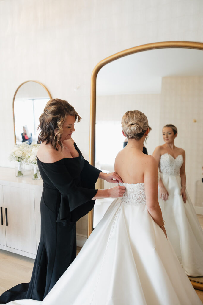 mother of the bride helping her with her wedding dress
