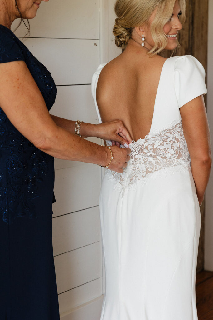 mother of the bride helping her with her wedding dress